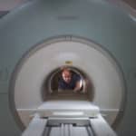 Scientist looking down the long tube of a donut shaped MRI scanner