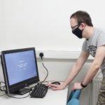 Chris Street in front of a computer pressing a key on the keyboard to make a response to an experiment running on the computer