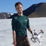 Dr Olly Bartlett holding a small drone on a glacier in the arctic.