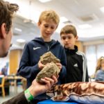 Kneeling man showing children some fossils