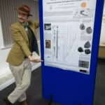 Standing besides a research poster