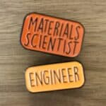 Two pin badges, which read "materials scientist" and "engineer"