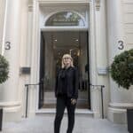 Blonde woman with a black suit standing in front of the Royal Academy of Engineering