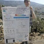 Photo of a girl holding up a poster with mountains in the background