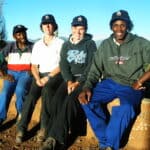 four team members on Lesotho project, sitting on a wall