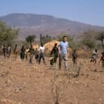 A photo of me walking in a field in Ethiopia followed by many local children.