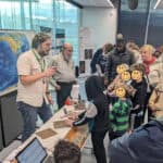 A photo of myself talking about earthquake hazards to members of the public standing in front of a world map.