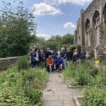 A group of people standing next to a church in some gardens