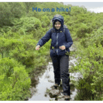 Woman dressed in rain coat wading through a puddle