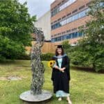 Woman in graduation cap and gown holding flowers