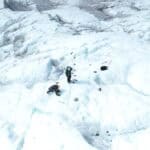 Two people set up a tall instrument on the surface of an ice sheet.