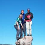 Three people standing on a boulder