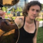 A woman holding a pair of sunglasses with a wasp attached