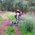 A woman falling off a bike carrying a ladder